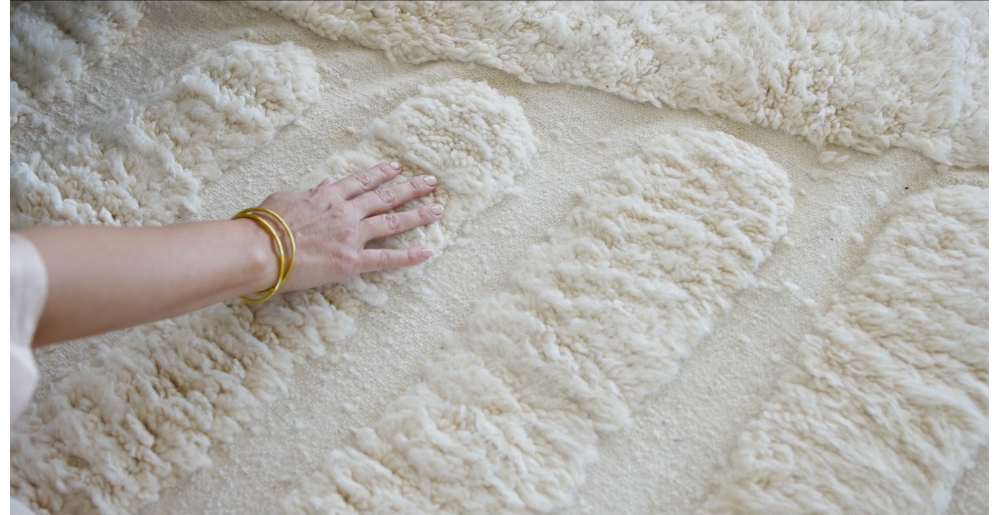 hand touching cream-colored moroccan wool rug